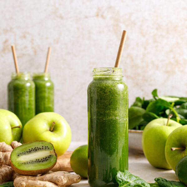 Smoothie. Healthy fresh raw detox spinach smoothie with green apple, kiwi and ginger in a bottles on a table. Healthy diet vegan food full of antioxidants