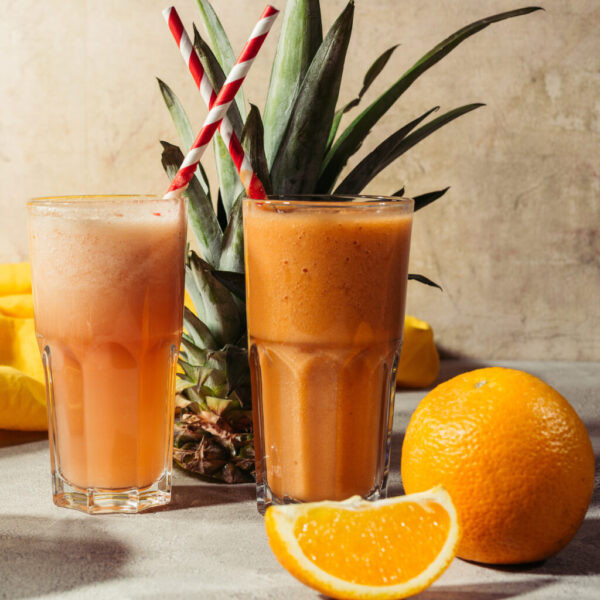 Tropical fruits and glasses with juice on table