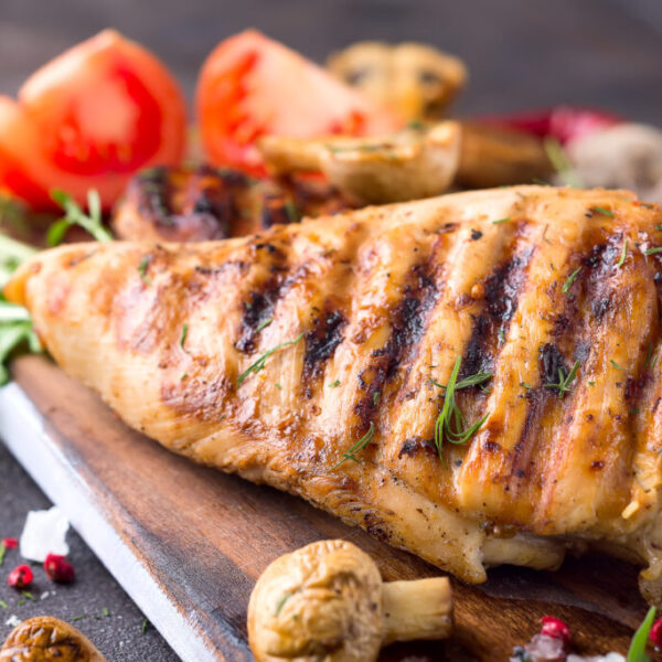 Grilled chicken fillets on wooden board on Gray concrete background. Healthy diet food concept, close up