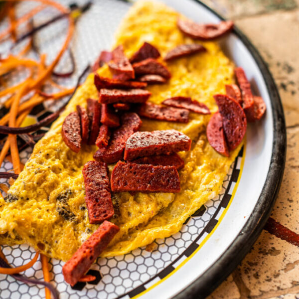 Omelet with sausage and vegetables in white plate.